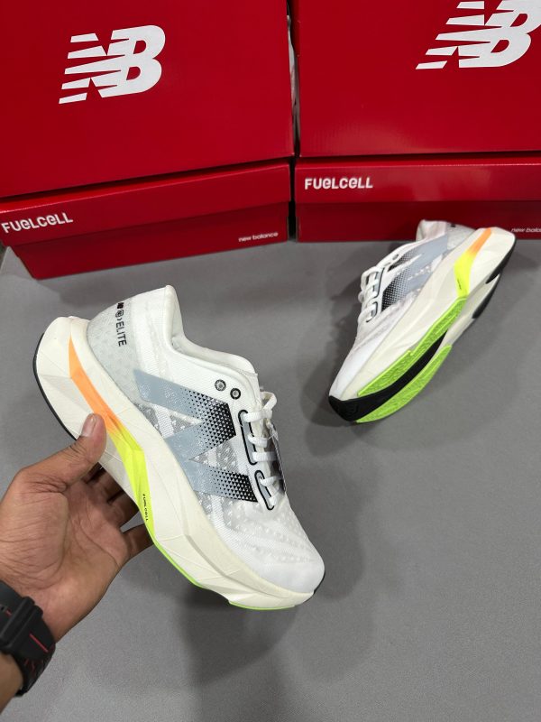 New Balance FuelCell SuperComp Elite v3 in white and silver with neon green and orange accents, displayed with FuelCell branded red shoebox in the background.