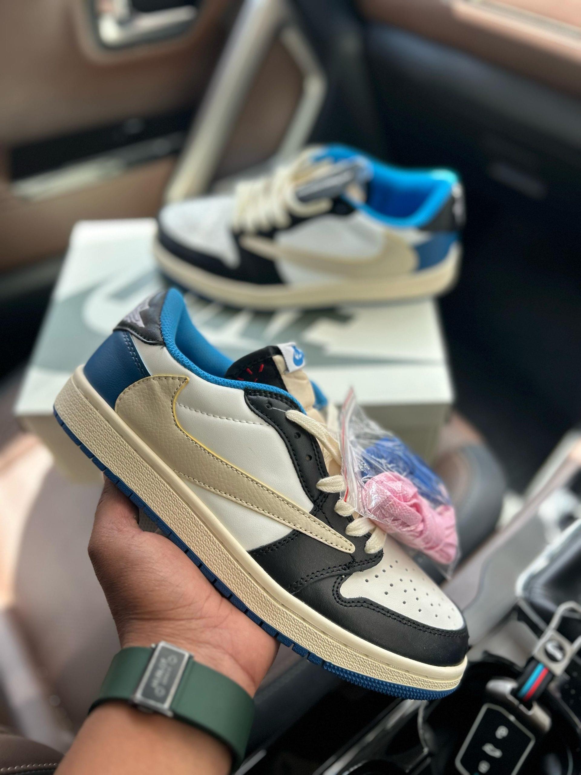 Nike Air Jordan 1 Low Travis Scott Fragment First Copy Shoes in black, white, blue and cream held in hand with extra laces