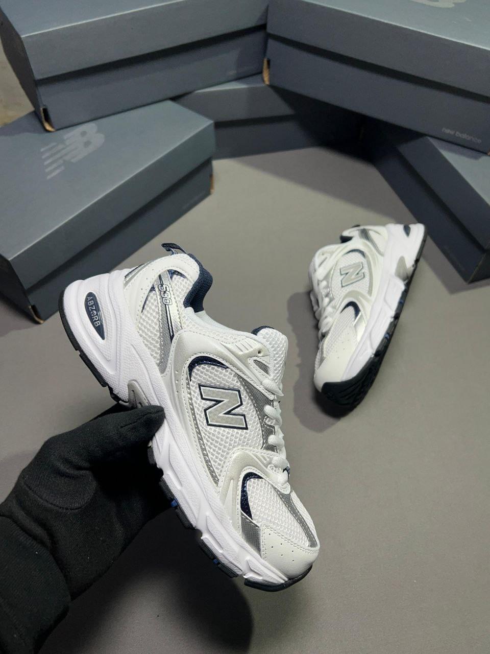 Premium quality New Balance 530 White Silver first copy sneakers on display with multiple shoeboxes